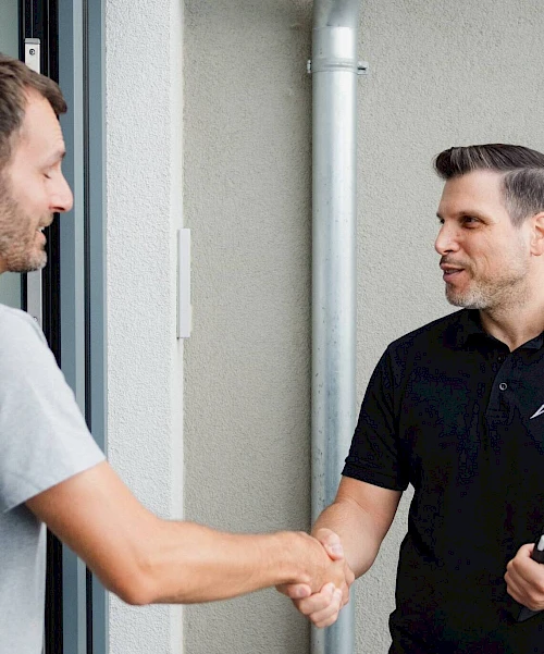 Geschäftsführer von AC Solar, Aldo Carro, begrüßt einen Kunden per Handschlag.