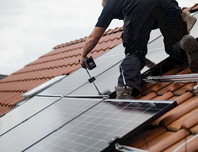 Monteur installiert Solarmodule auf einem Hausdach.